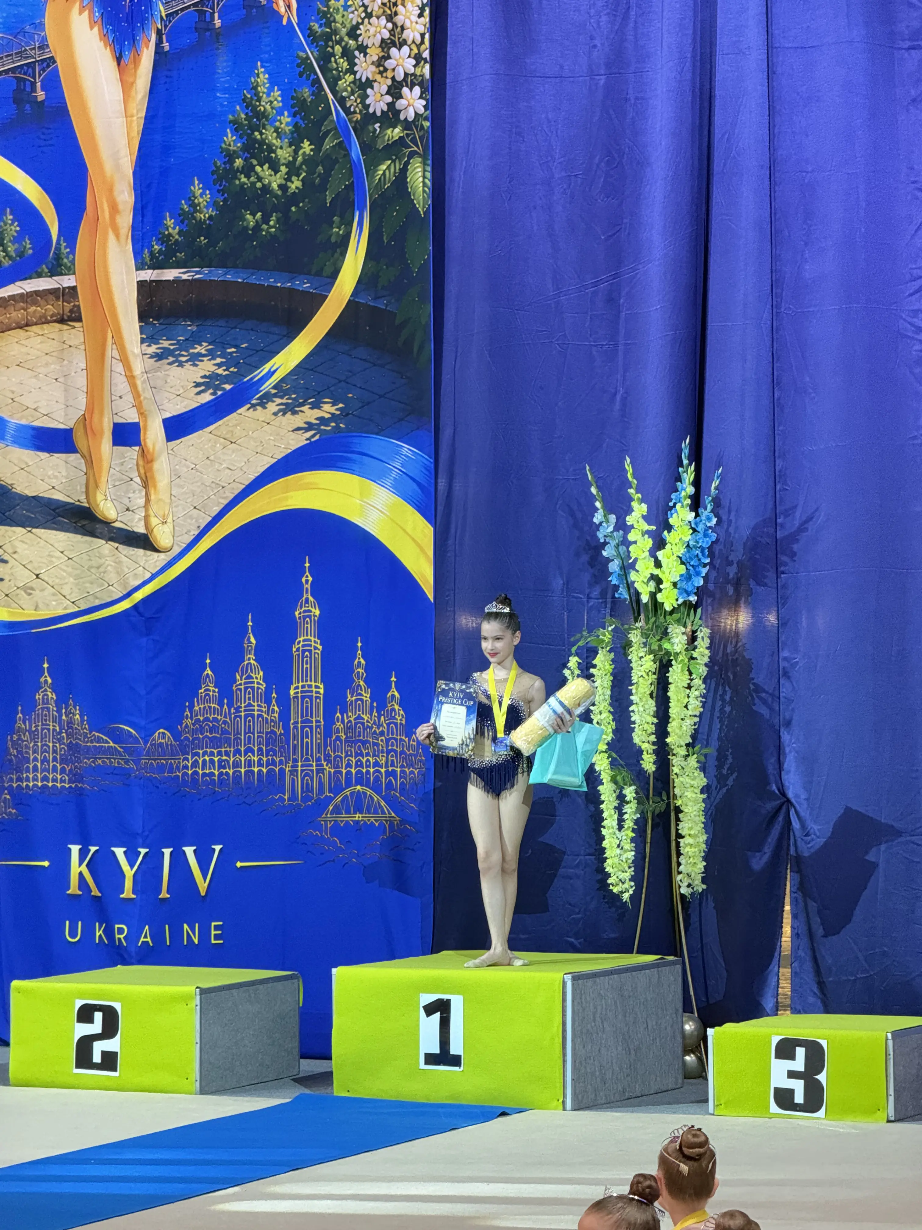 Гімнастка Estela усміхається з дипломом і медаллю на пʼєдесталі Kyiv Prestige Cup